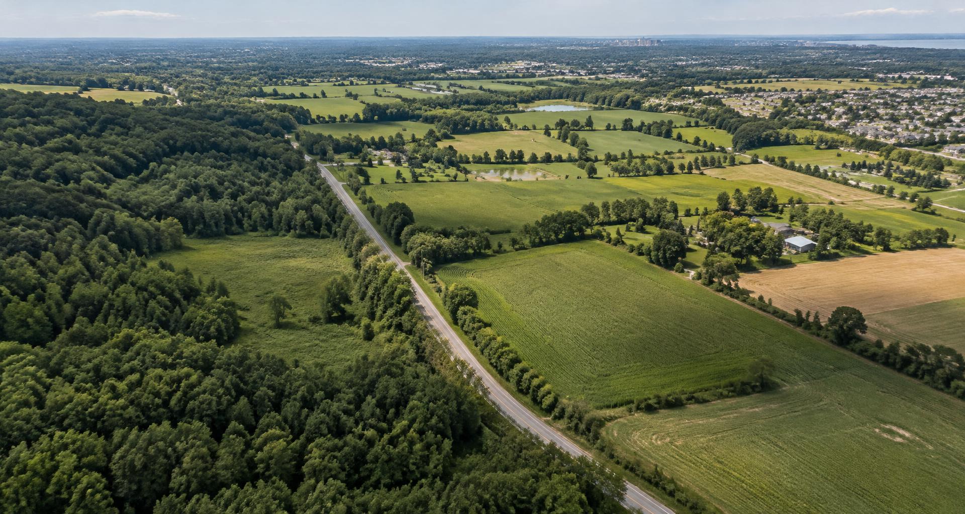 Illustrative Southern Ontario landscape showing fields, tree belts and an urban edge; not a property offered for sale